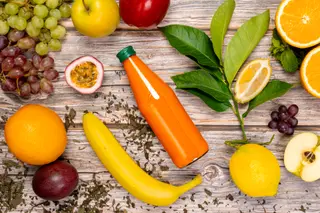 Staged shot with a bottle of multivitamin juice and fresh fruits.